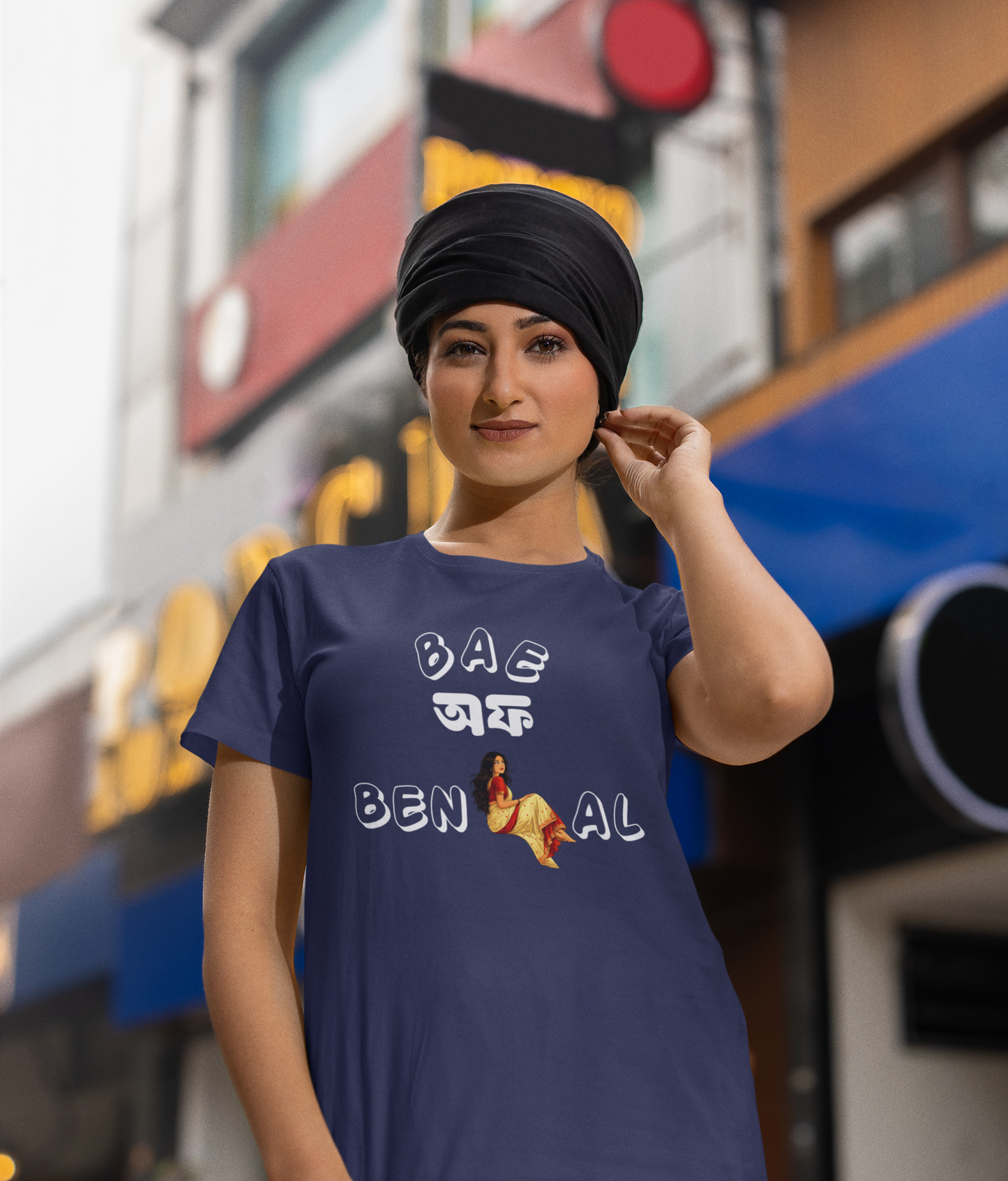Woman wearing a royal blue t-shirt with 'Bae of Bengal' graphics in an urban setting