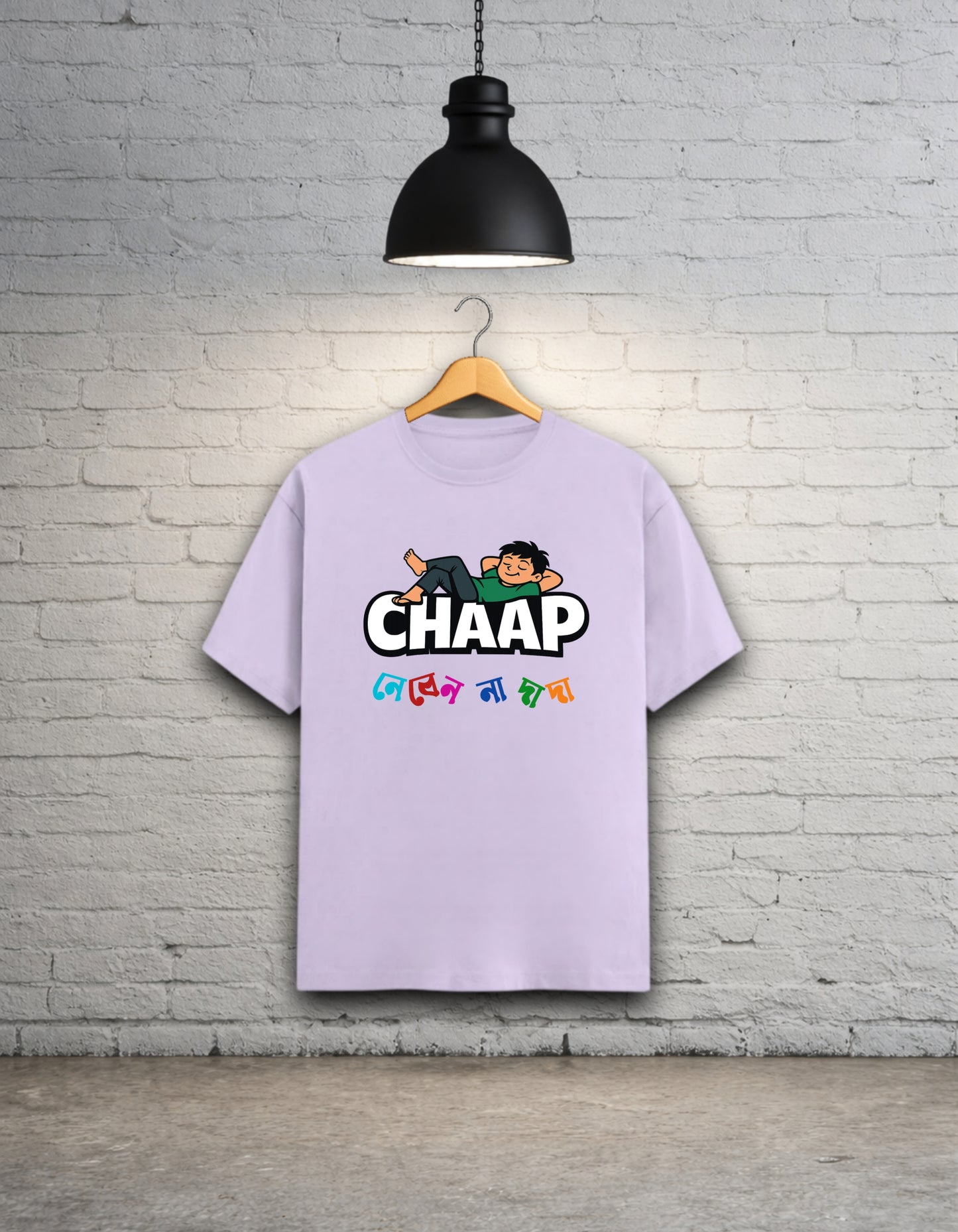 Lavendar t-shirt with 'CHAAP nebenna dada' bengali graphic design hanging on a brick wall.