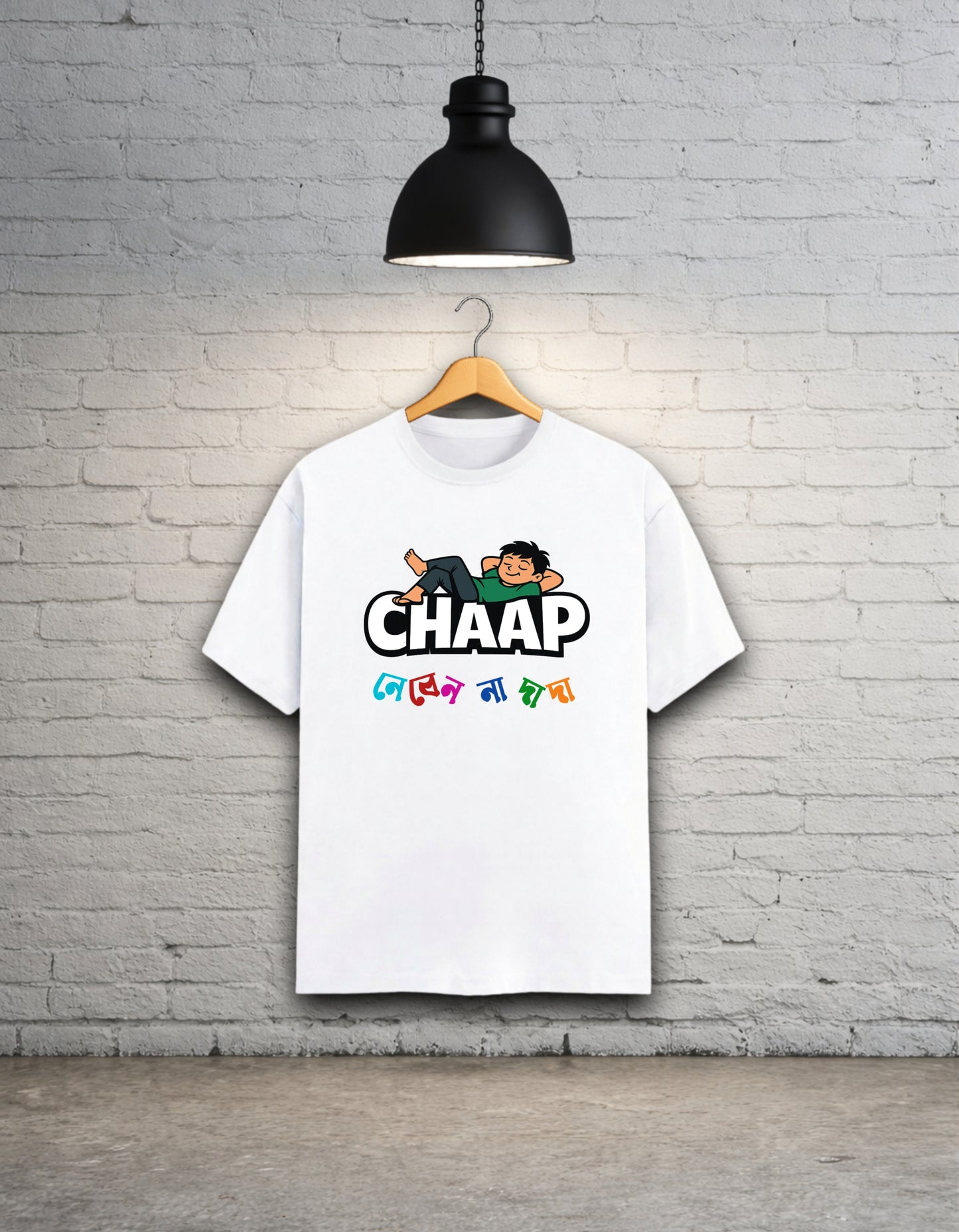 White t-shirt with 'CHAAP nebenna dada' bengali graphic design hanging on a brick wall.